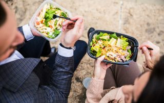 Två personer äter matlåda utomhus